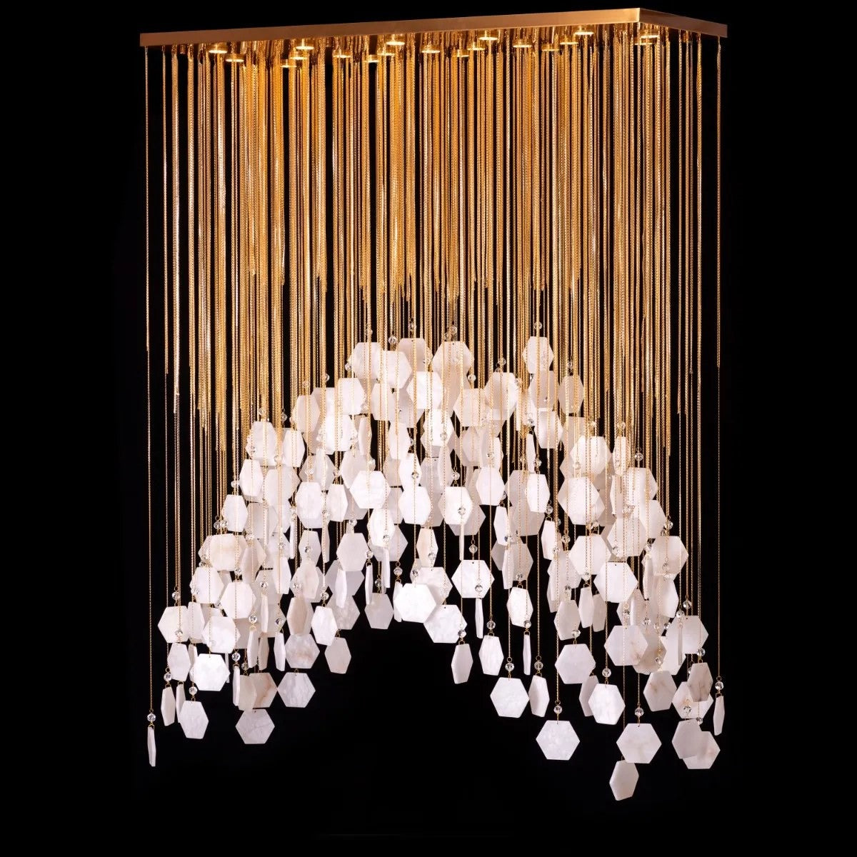 Rectangular chandelier of vertical gold chains ending in an arched wave of white marble-veined hexagonal tiles