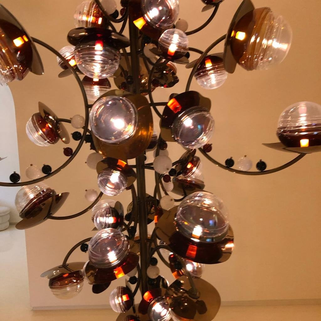 Close-up of the branching chandelier showing curved bronze stems, ribbed clear and amber glass globes, brass disc reflectors and glass beads