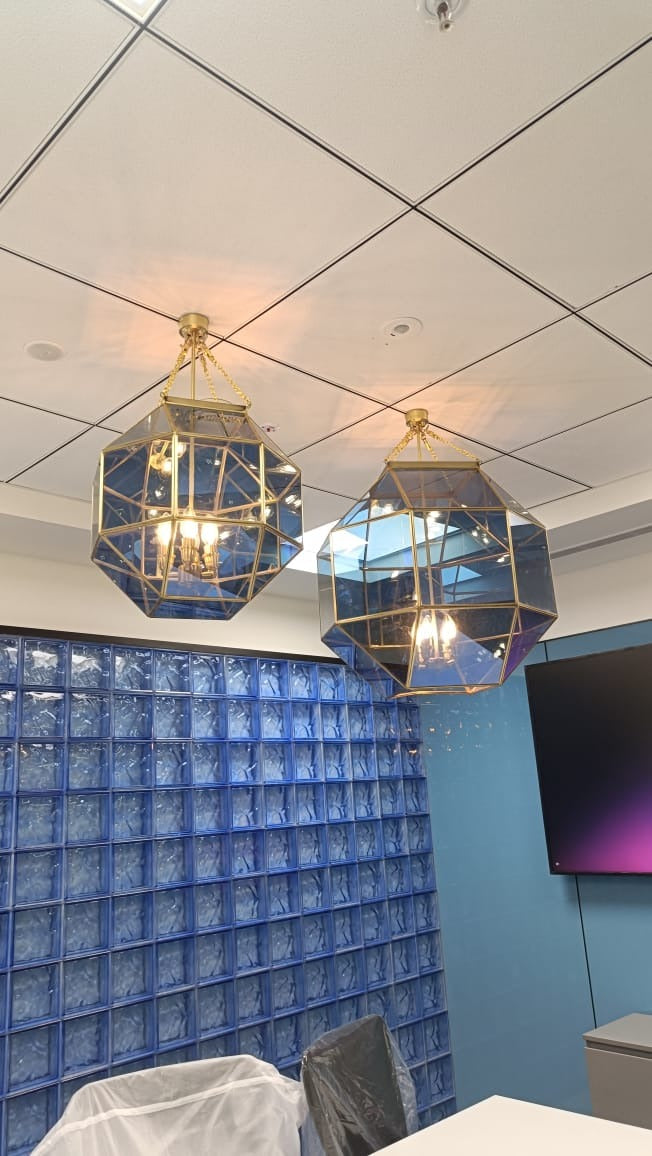 Custom brass and blue-tinted glass geometric pendants installed in a corporate meeting room, Hyderabad