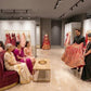 3D design visual – sofa pod: salespeople showing a bridal lehenga to the seated family, Aari Tari, Jaipur