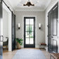 Entrance foyer installation showing the four-petal semi-flush chandelier in a dark bronze finish with frosted white shades mounted on a white ceiling above a glazed front door