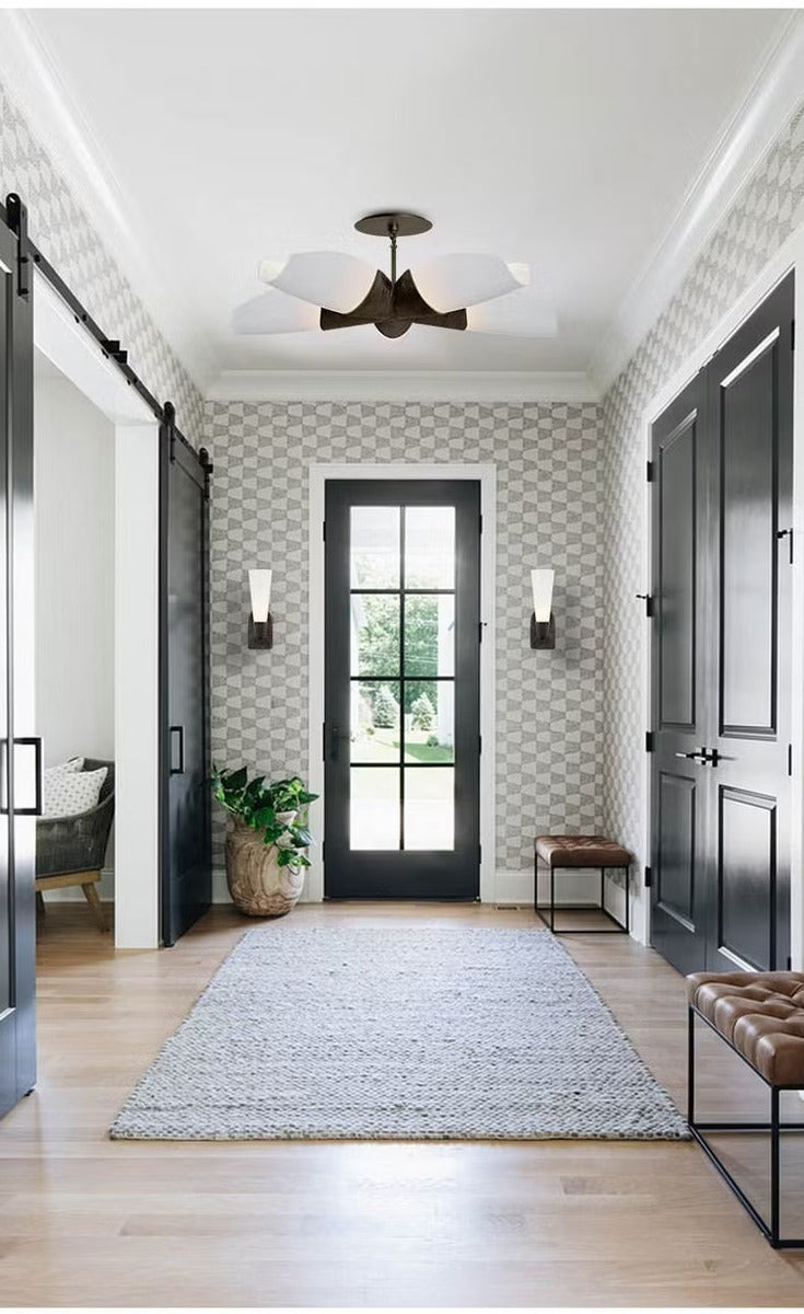 Entrance foyer installation showing the four-petal semi-flush chandelier in a dark bronze finish with frosted white shades mounted on a white ceiling above a glazed front door
