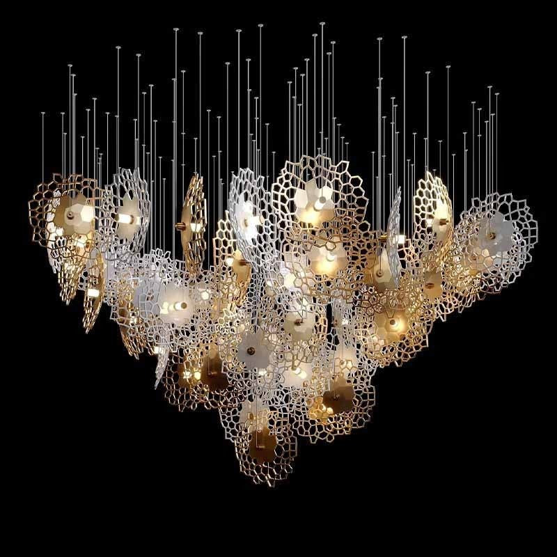 Wide V-shaped cluster of vertically oriented white and gold openwork honeycomb iron discs with warm central lamps