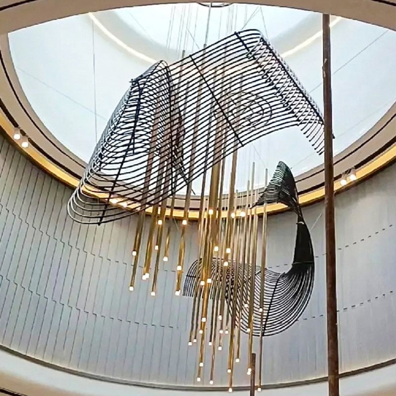Upward angle showing the upper curved black parallel-wire canopy and cascading brass LED rod pendants