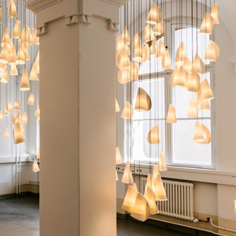 Wide architectural view of the matte-white conical pendant cluster hanging across a high-ceilinged columned hall