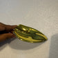 Close-up of a single sculpted curved glass leaf element finished in a reflective metallic gold glaze