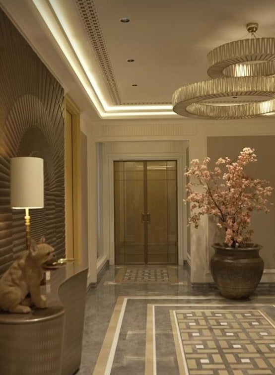 Mid-range view of the stacked geometric brass ring chandelier glowing warmly in a panelled foyer