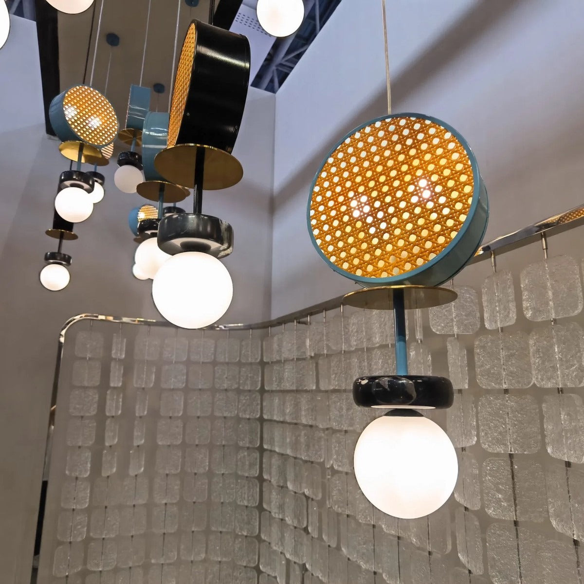 Side perspective of the multi-drop pendant units showing the backlit golden hexagonal mesh, brass plate, and opal sphere