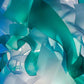 Close-up detail of the curling translucent seafoam-green, aqua, and frosted white wave ribbons glowing from within