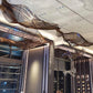 Perspective view showing multiple three-dimensional bronze metal slat wave forms hanging in sequence