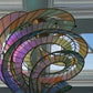 Close-up of the interlocking curved bronze tracks holding pebbled art-glass segments in amethyst, amber, and sage green