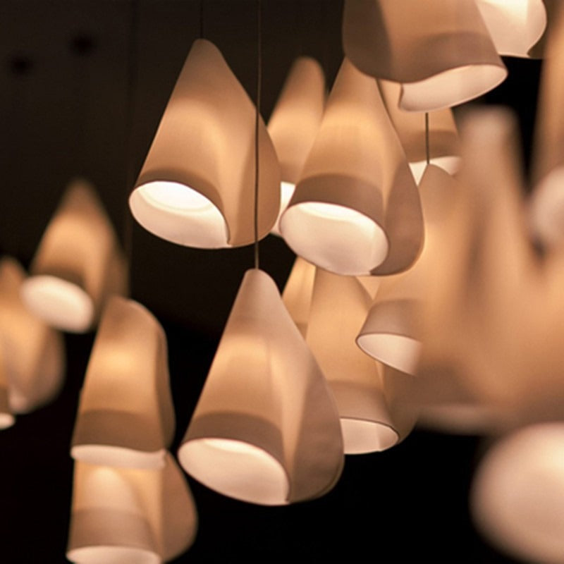 Close-up view of the wrapped bone-white translucent conical shades glowing warmly from within against a dark background