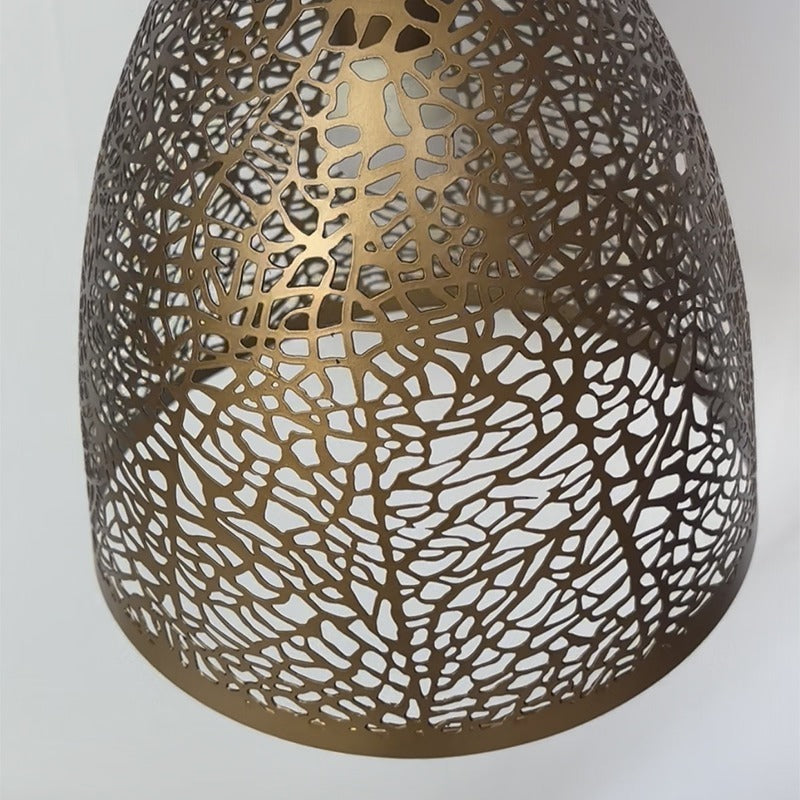 Close-up detail of the antique brass shade highlighting the organic leaf-vein and cellular cutout pattern