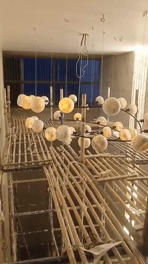 The marble globe spiral chandelier unlit, hanging on fine clutch wires during installation