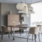 Three-pendant cluster of white ribbed silk-paper tiered lanterns with black wooden neck rings hanging above a round dining table and grey chairs