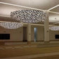 Wide view of multiple four-tier geometric lattice and faceted glass ring chandeliers installed across a large pillared hall ceiling