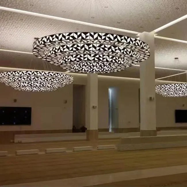 Wide view of multiple four-tier geometric lattice and faceted glass ring chandeliers installed across a large pillared hall ceiling