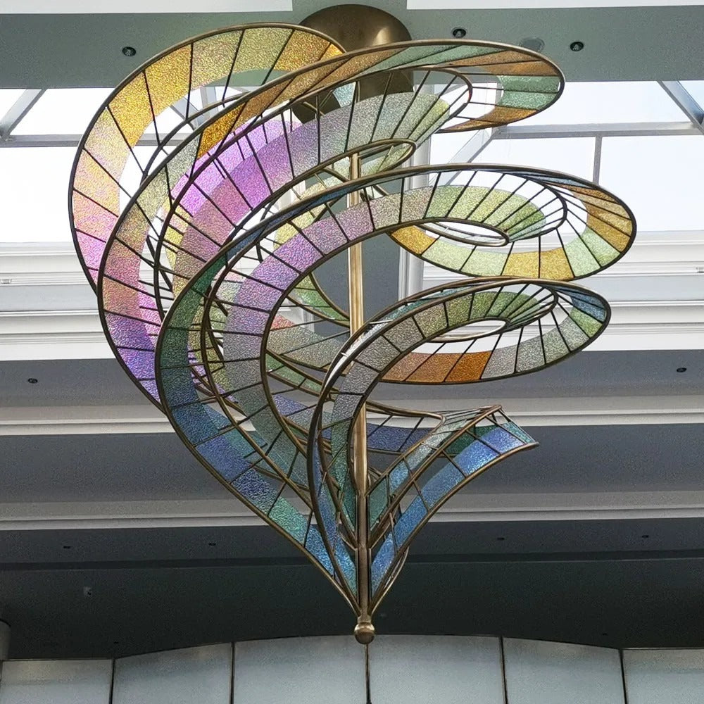 Upward perspective showing the inverted-cone vortex of colourful textured glass ribbons converging at a lower bronze finial