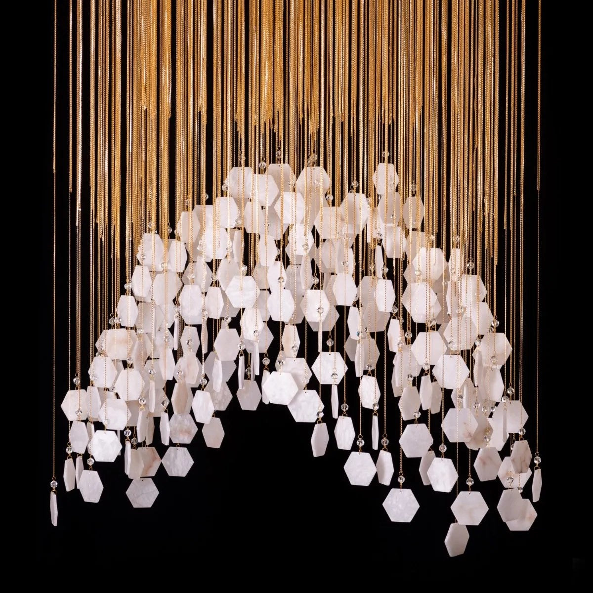 Close-up detail of the white veined hexagonal tiles, crystal bead connectors, and fine gold suspension chains