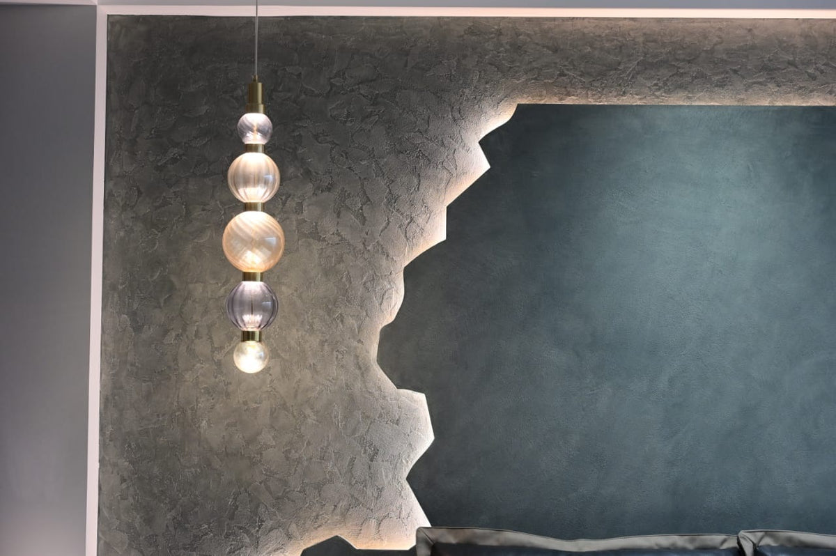 Stacked glass-globe pendant against a textured wall feature with hidden LED backlighting