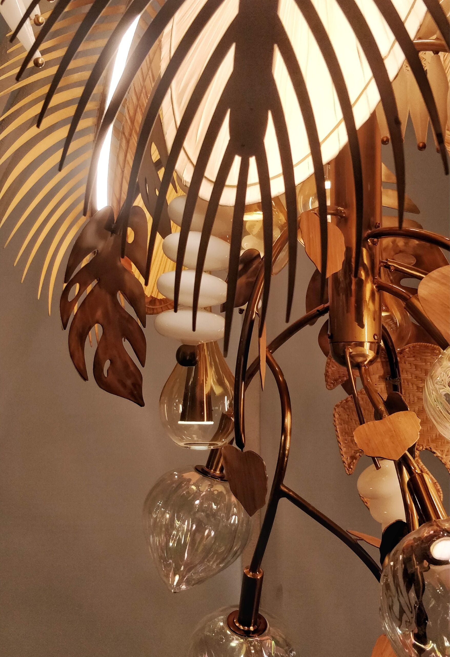 Detail of rattan leaf shades and hand-blown glass drops on the antique brass frame