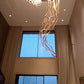 Full drop of the feather glass chandelier past the tall windows of the double-height living room
