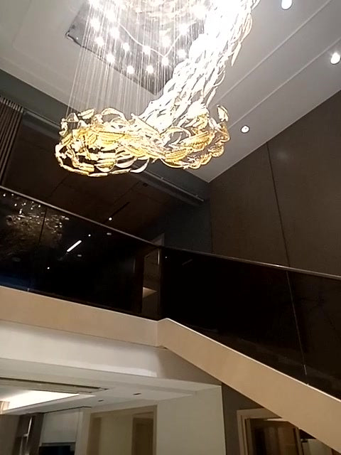 Feather glass spiral chandelier lit above the staircase of a double-height home in Guwahati