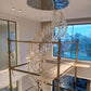 Glass ribbon spiral hanging from its round mirrored canopy across the double-height void, during installation