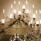 Close-up detail of hand-blown frosted glass leaves and candle-flame diffusers on the chandelier's brass branch frame