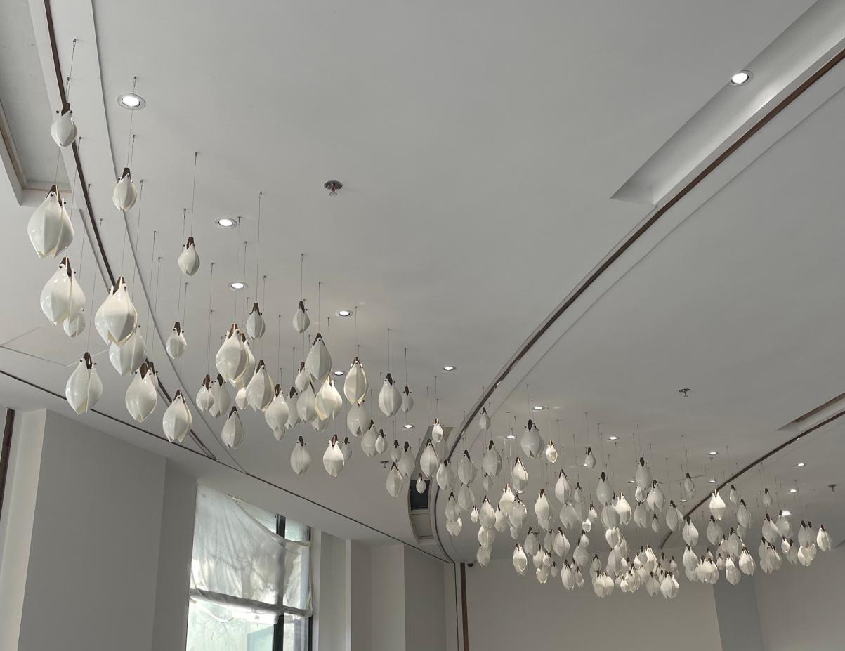 Frosted calla drop cascade chandelier installed along a curved reception ceiling