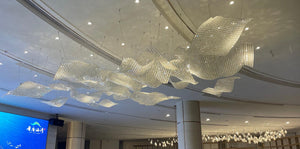 Opaline sequin drift chandelier draped across a grand lobby ceiling