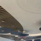 Row of pleated disc drum pendant chandeliers repeated across a ceiling