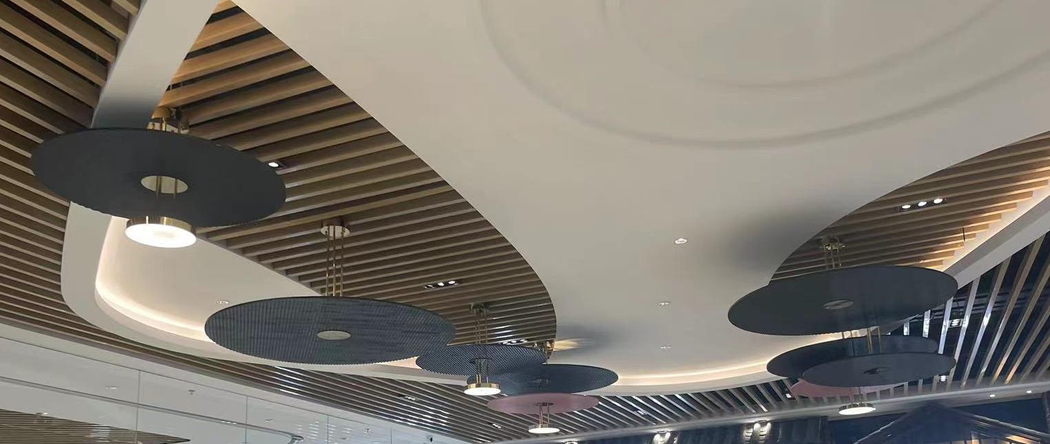 Row of pleated disc drum pendant chandeliers repeated across a ceiling
