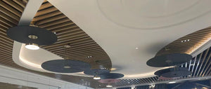 Row of pleated disc drum pendant chandeliers repeated across a ceiling