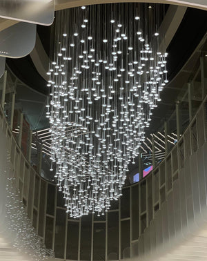 Cascading rainfall LED pin chandelier descending through a multi-storey atrium void