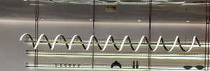 Serpentine spiral LED ribbon chandelier suspended above a bar counter