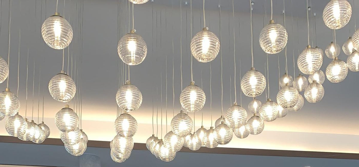 Close-up of ribbed glass orbs in the cascading chandelier catching warm light