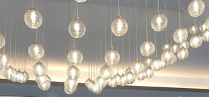 Close-up of ribbed glass orbs in the cascading chandelier catching warm light