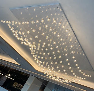 Cascading ribbed glass orb chandelier flowing across a rectangular ceiling recess