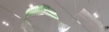 Ombre strand ribbon sculpture chandelier looping across a lobby ceiling