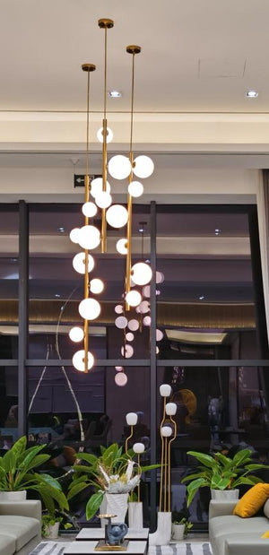 Graduated glass orb drop chandelier hanging above a lobby seating and planter area