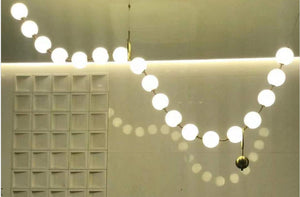 Luminous orb garland chandelier draped in a wave shape along a feature wall