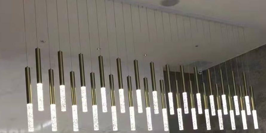 Staggered brass tube cluster chandelier with bubble-textured diffuser tips