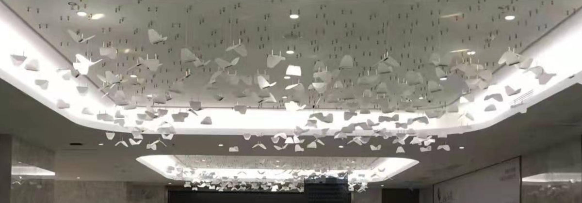 Scattered folded-panel cluster chandelier spanning a lobby ceiling