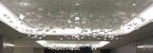 Scattered folded-panel cluster chandelier spanning a lobby ceiling