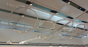 Interlocking crystal ring cluster chandelier suspended from a ceiling grid