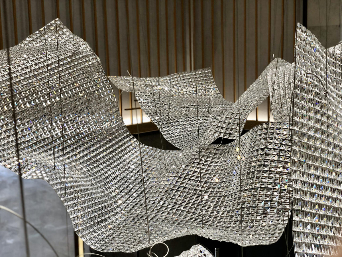 Folded crystal mesh sail chandelier billowing across an atrium ceiling