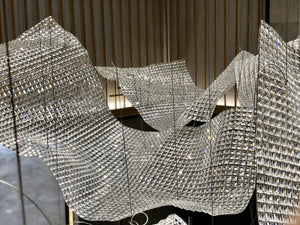 Folded crystal mesh sail chandelier billowing across an atrium ceiling