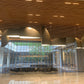 Bronze sail-form pendant chandelier with curved metal panels staggered along a wood-panelled reception ceiling