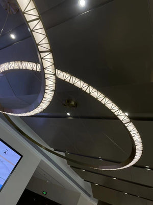 Halo ring cluster chandelier with illuminated brass rings grouped overhead in a sales gallery